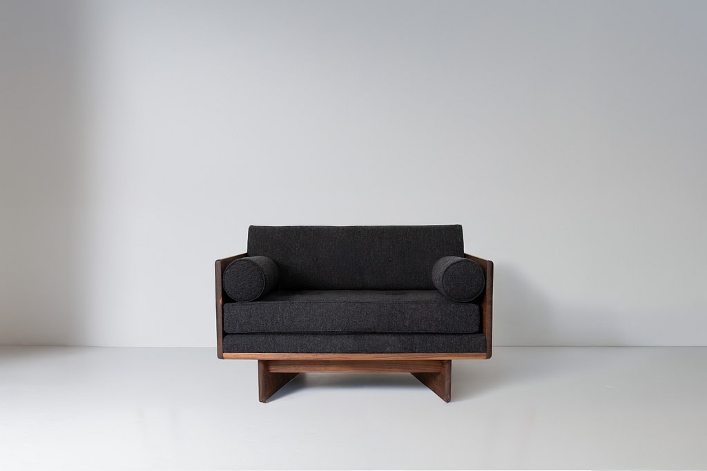 Kalon no6 series chair black walnut Dark Gray Upholstered Armchair with a Wooden Frame Centered Against a Pale Gray Wall in a Minimal Roomui Setting