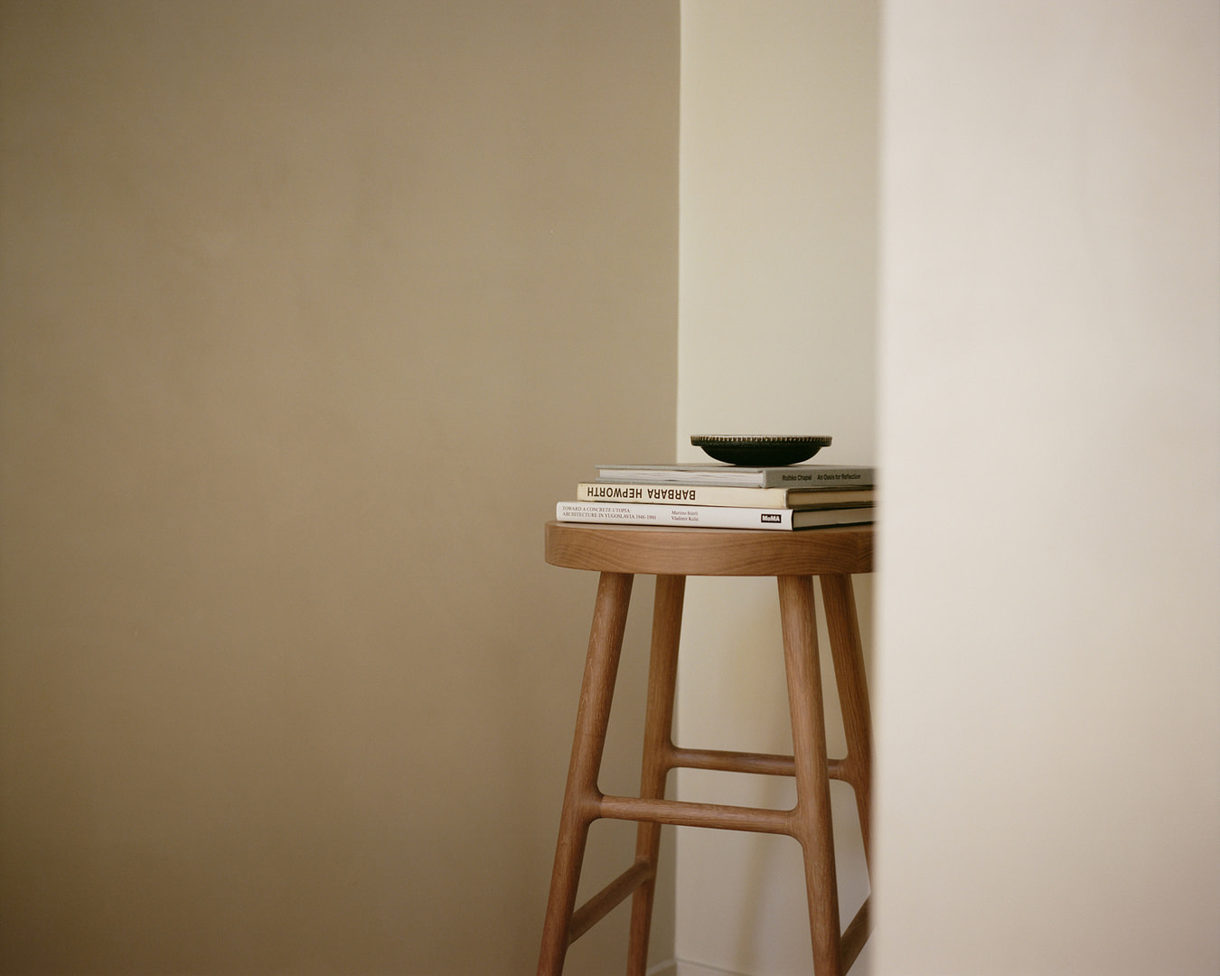 Kalon boughbarstool 1 Bough Bar Stool in White Oak Used As a Side Table in a Beige walled Corner Stacked Barbara Hepworth Books and a Dish on Top