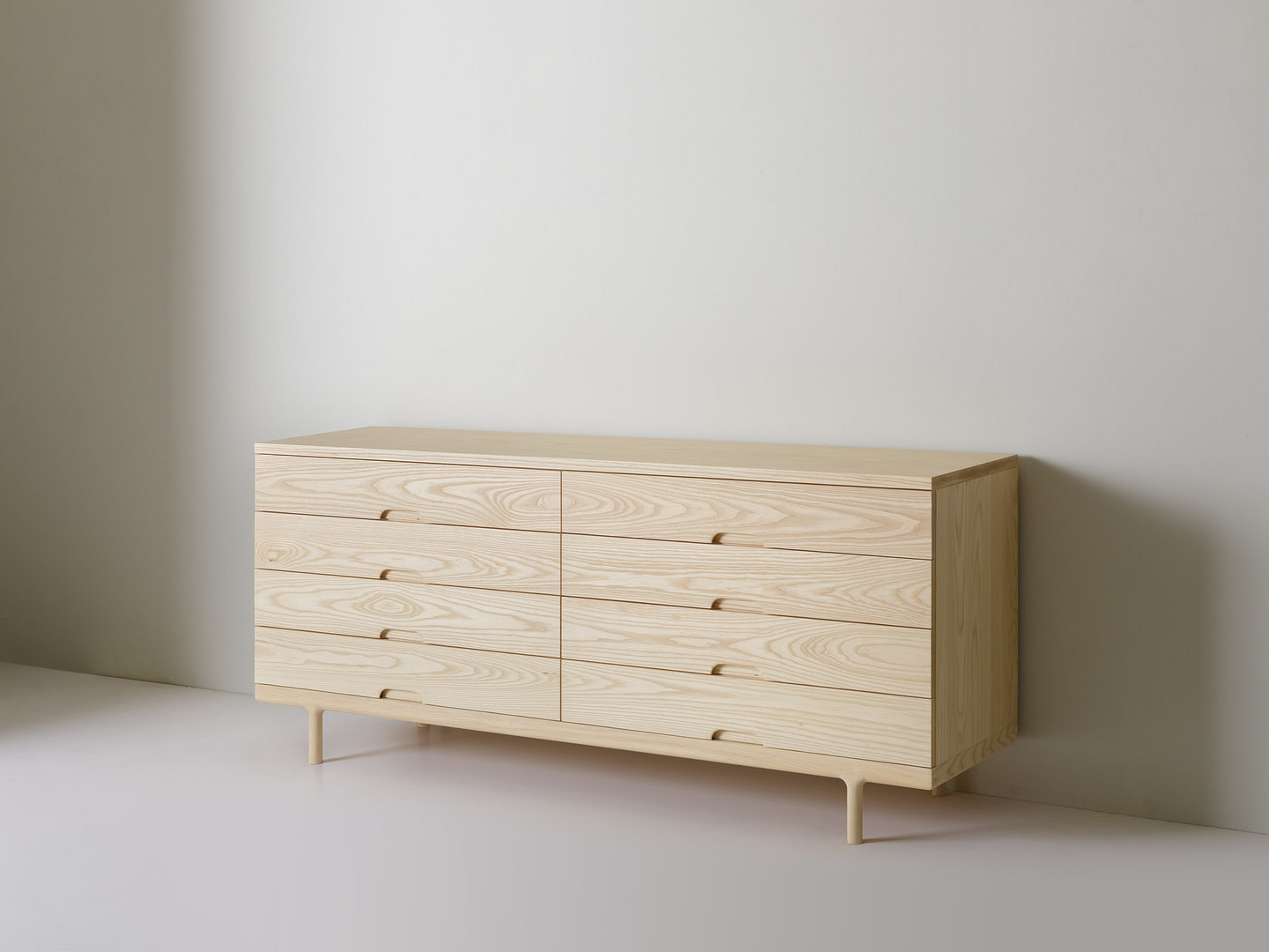 Light Wood Dresser with Eight Shallow Drawers and Tapered Legs Against a Pale Gray Wall in a Minimal Room Setting |  | Kalon Studios Us