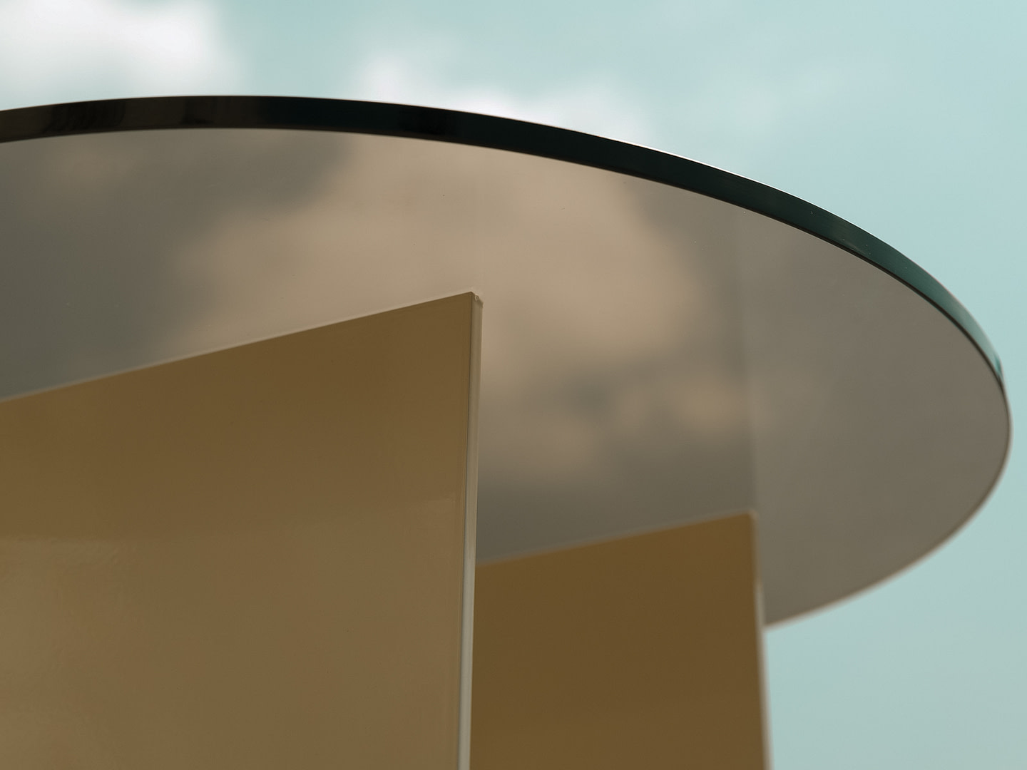 Material Studies I Side Table, close view up at the bronzed-glass top and pale aluminum base against sky