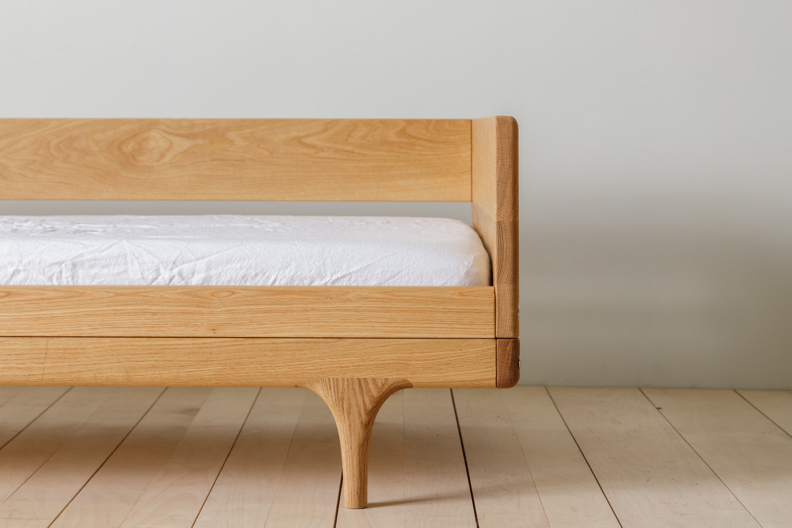 Kalonstudios caravan conversionkit naturalfinish 4 Caravan Divan in White Oak Side Close up with Backrest Sculpted Leg Walnut Corner Cap on a Maple Plank Floor