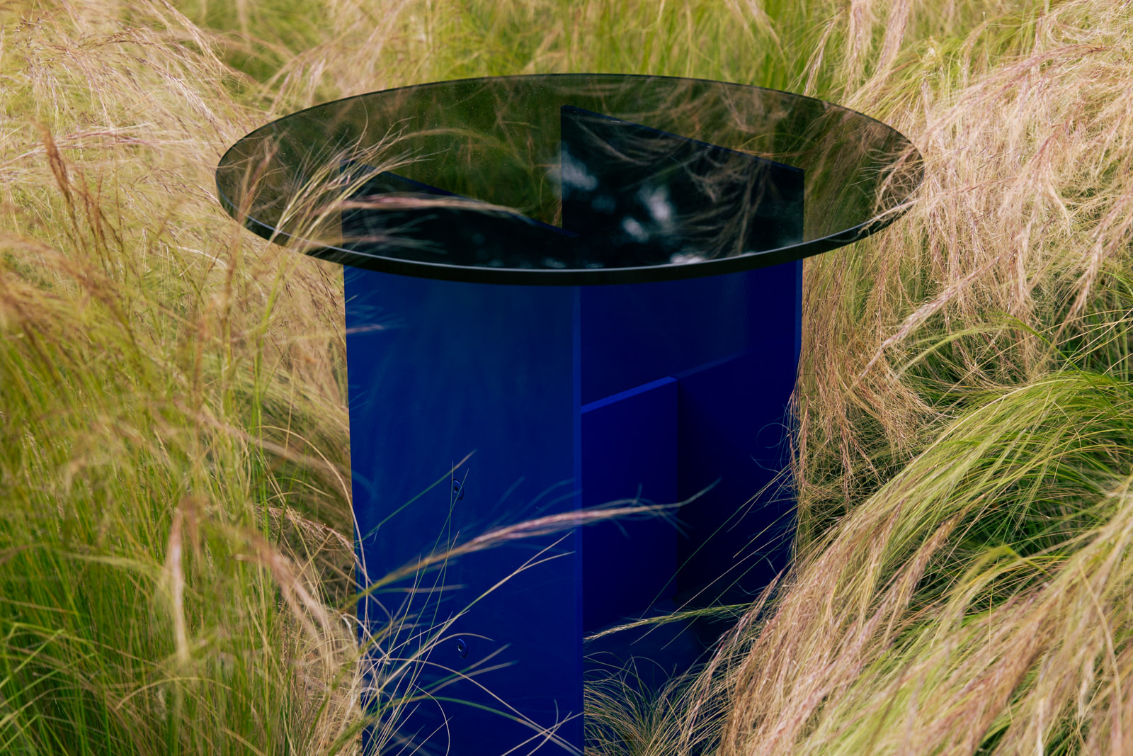 Material Studies I Side Table in lapis blue aluminum, bronzed-glass top, set outdoors among tall grasses