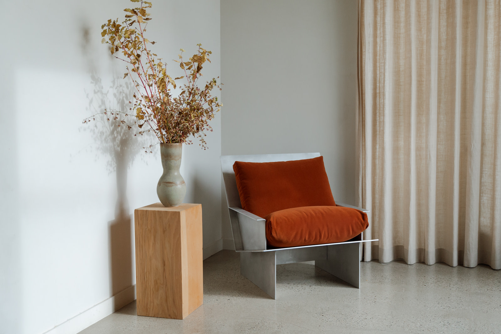 Kalonstudios materialstudies rawaluminum 5 Material Studies I Chair Raw Aluminum and Rust Velvet in a Corner with Dried Branches on a Wood Plinth