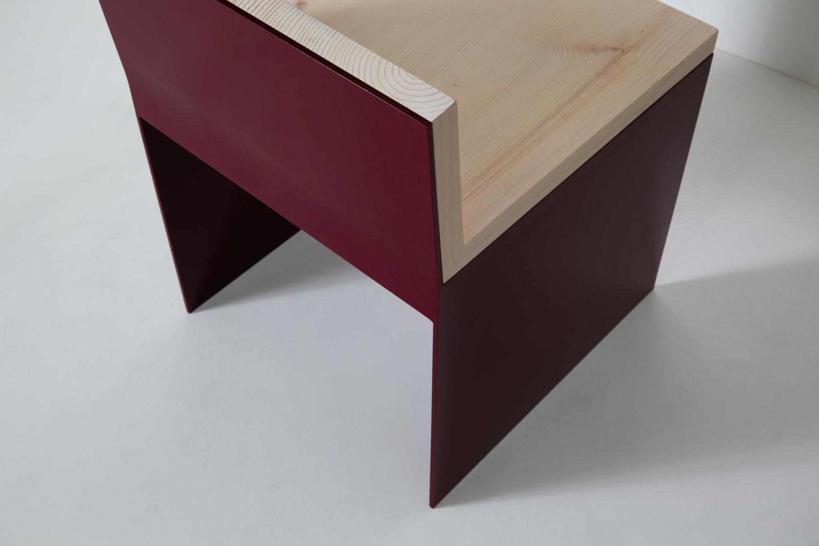 Material Studies I Dining Chair, close detail of the sugar pine seat edge joining the oxblood aluminum panel