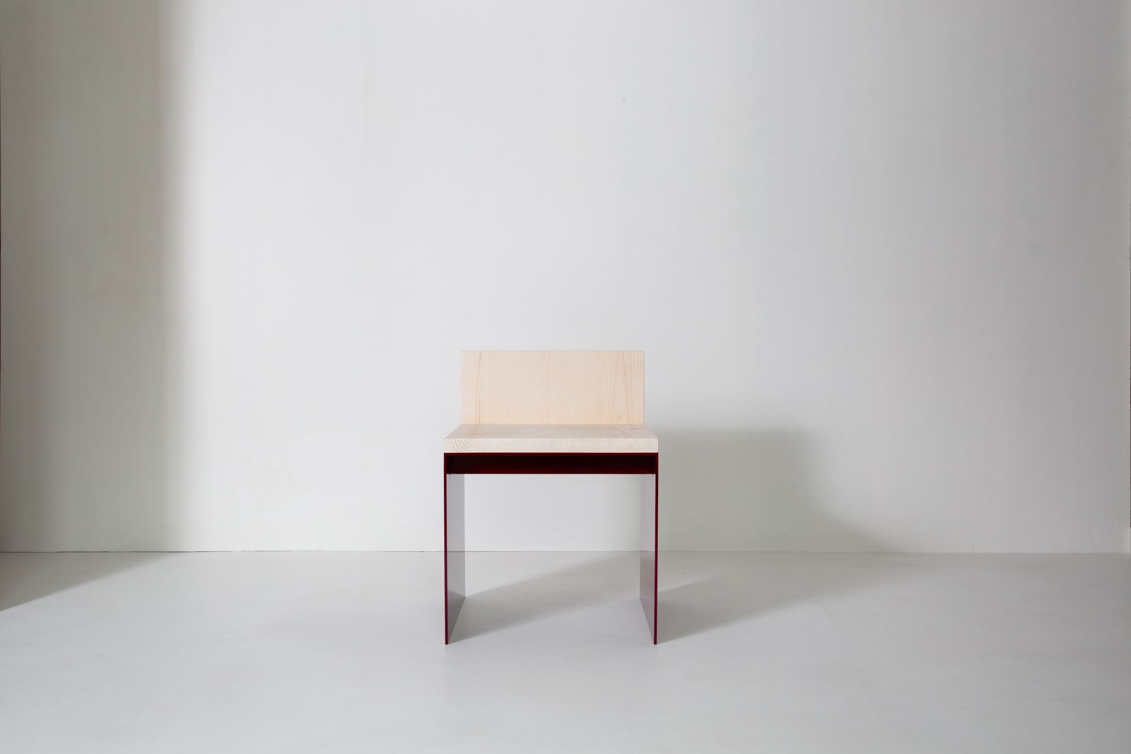Material Studies I Dining Chair, oxblood aluminum frame and sugar pine seat with a low pine back, front view