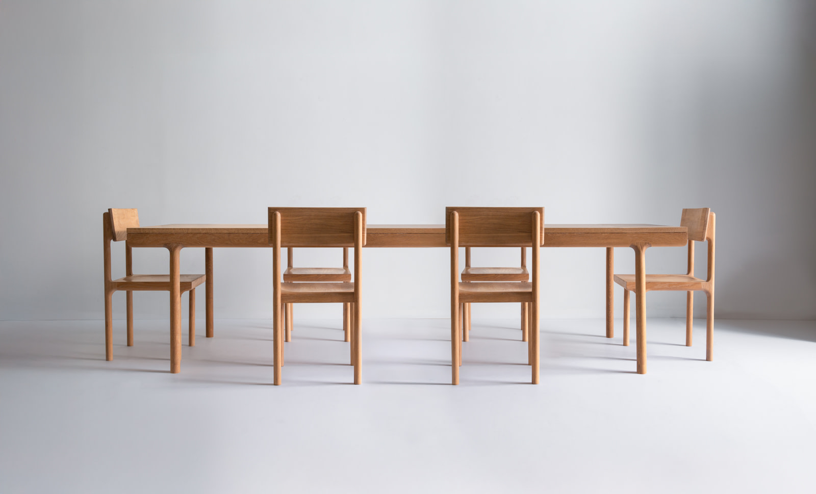 Long Wooden Dining Table with Six Matching Chairs in a Bright Minimalist Room in a Studio Setting |  | Kalon Studios Us