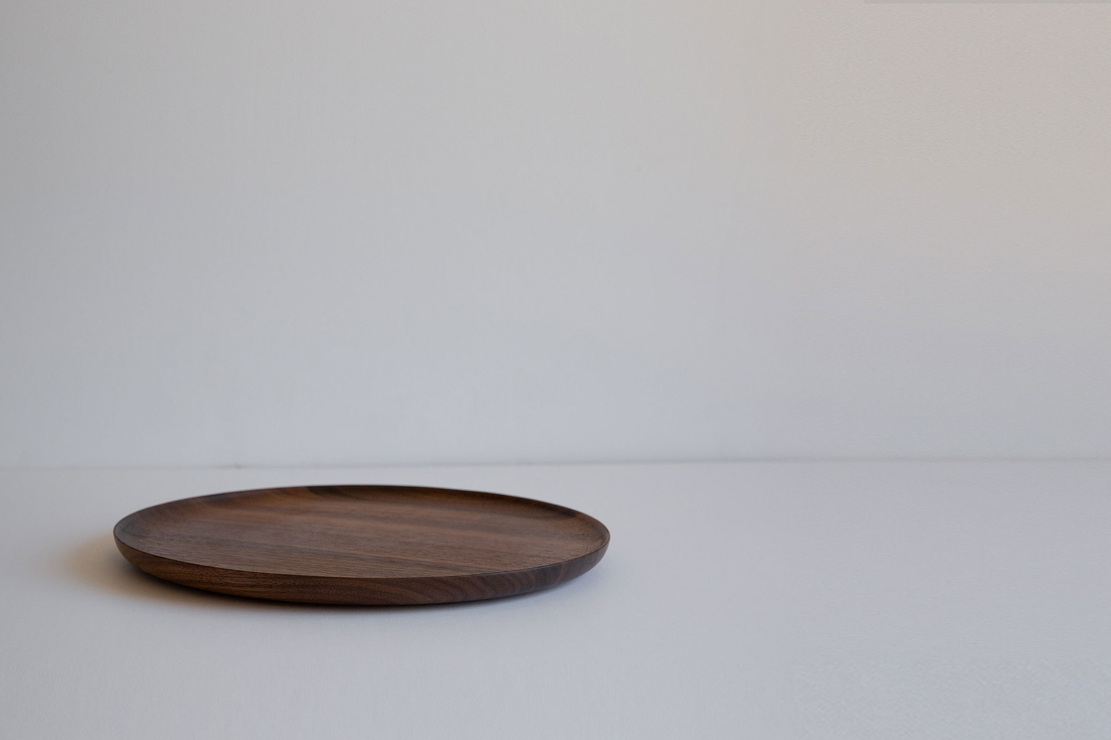 11-inch roasted plate in dark-toned wood, empty with a low upturned rim, on a white studio backdrop.