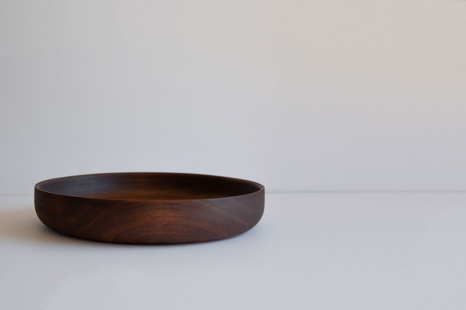 14-inch roasted serving bowl in dark wood, empty with a low wide profile, on a white backdrop.
