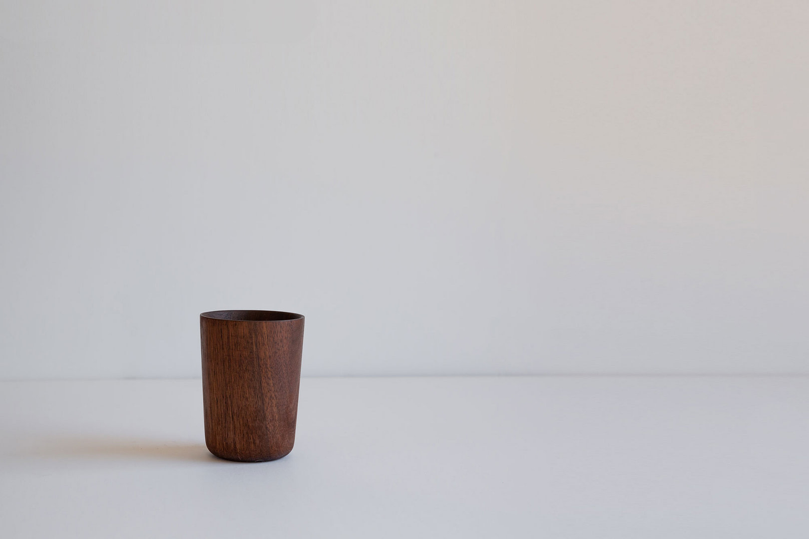 Cup walnut fullbleed Roasted Cup in Dark toned Wood Standing Upright a Tall Turned Tumbler Form on a White Studio Backdrop