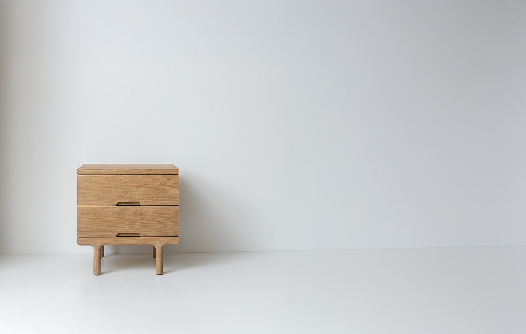 Simple sidetable whiteoak leftaligned Simple Side Table in White Oak with Carved Wood Finger pulls and Wood Legs Off center Left in a Wide Frame Two Drawers