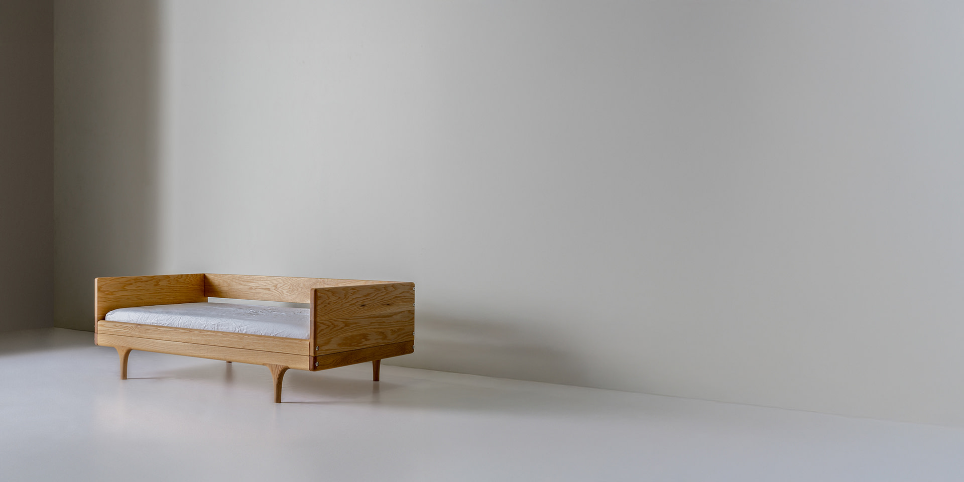 Kalonstudios caravan conversionkit leftaligned naturalfinish Caravan Divan in White Oak with Walnut Caps Backrest Configuration Off center to the Left on a White Studio Floor