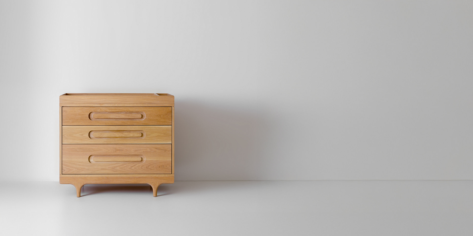 Kalonstudios caravan changingtray naturalfinish leftaligned Caravan Dresser in White Oak with Changing Tray Accessory Installed on Top Off center to the Left on a White Floor