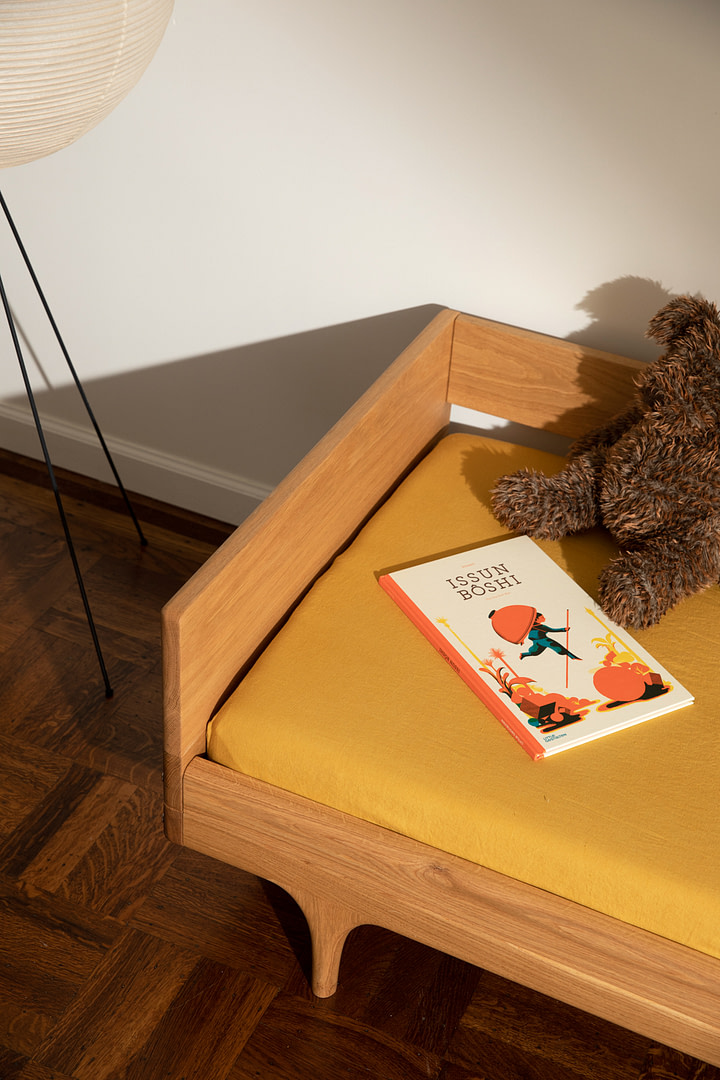 Kalonstudios caravan conversionkit naturalfinish 9 Caravan Divan in White Oak with Mustard Sheet Issun Bōshi Book and Brown Plush Teddy Parquet Floor with Black Floor Lamp