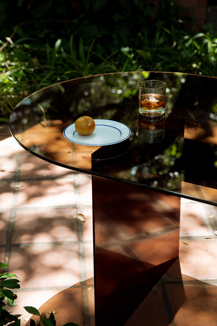 Materialstudies diningtable insitu 3 Material Studies I Dining Table Close Outdoor View of the Bronzed glass Top Set with a Plate and Glass