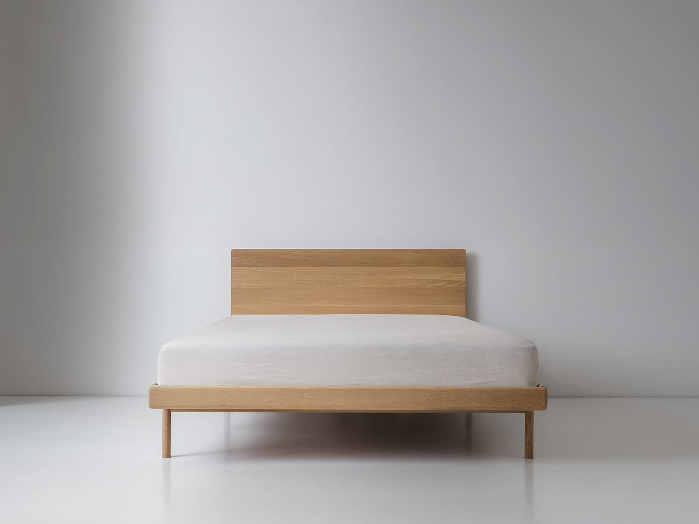 Simple Bed in white oak with panel headboard and white mattress plain wood legs centered front wider king framing
