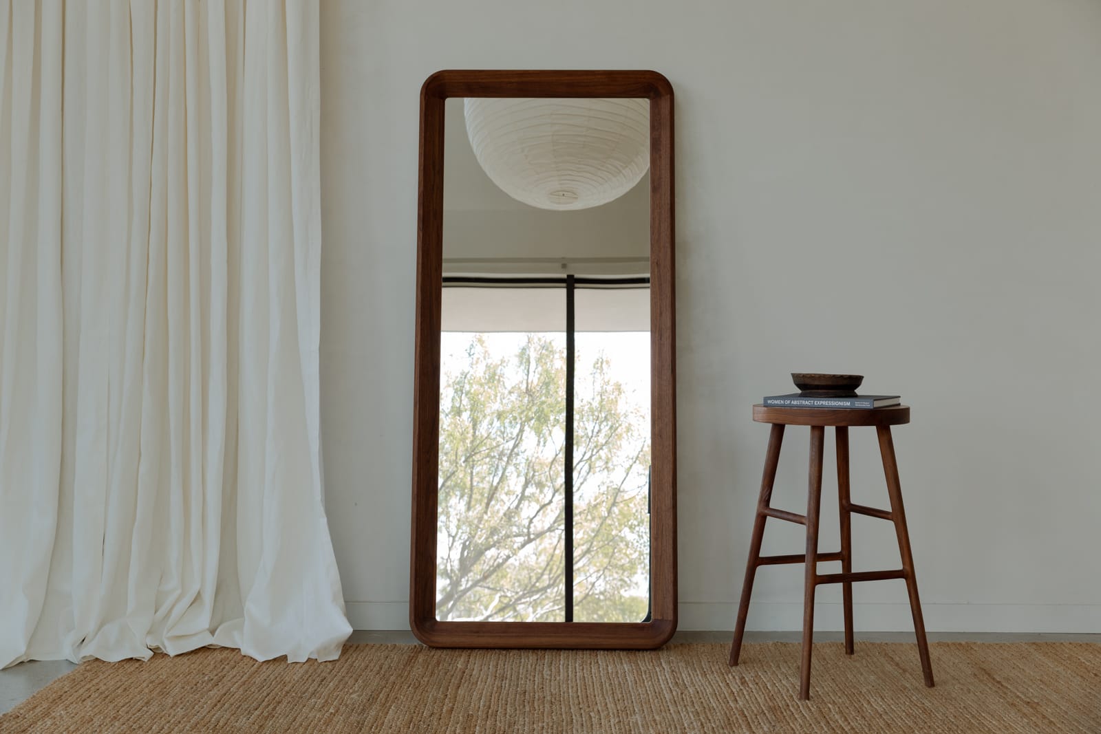 Simple Mirror in walnut tall leaning floor mirror in a residential interior reflecting a paper lantern linen curtains