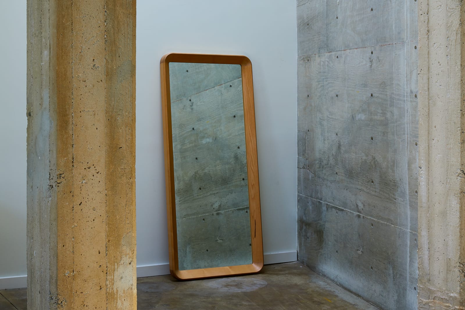 Simple Mirror in white oak tall leaning floor mirror with a rounded corner frame against a wall on a white floor